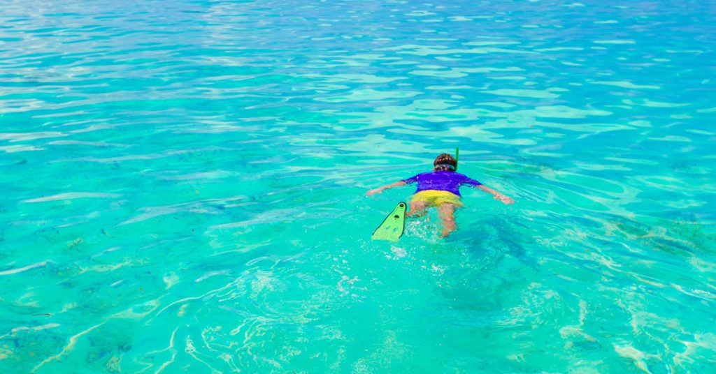 Persona haciendo esnórquel en aguas de color turquesa.