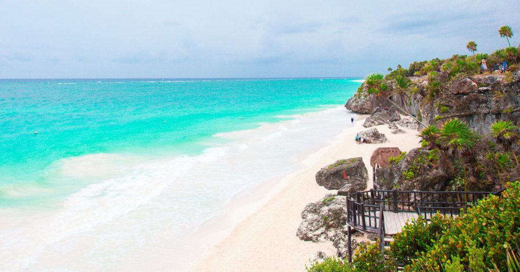 Playa de Tulum con un marcado contraste entre la arena blanca de la playa y las aguas color turquesa.