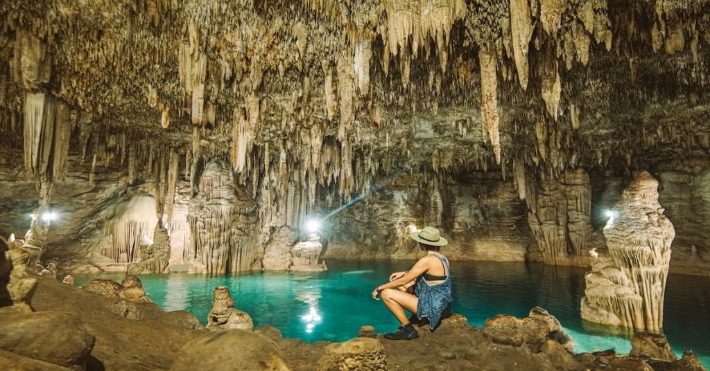 mujer contemplando interior de cueva con estalactitas
