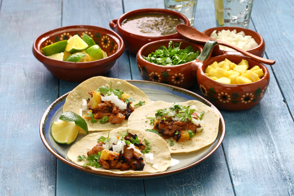 Plato de tacos al pastor con guarniciones.