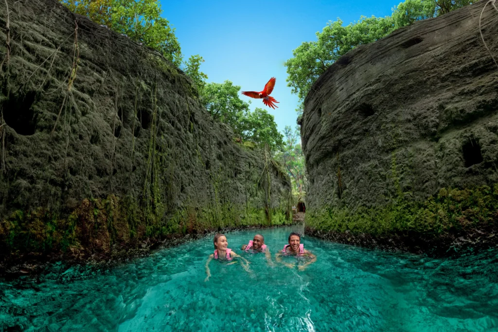 Turistas felices nadando en uno de los cenotes del Parque Xcaret en la Riviera Maya.